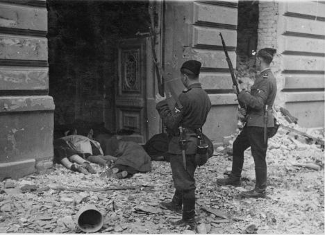 Guards peer into a doorway at bodies of Jews killed during the uprising